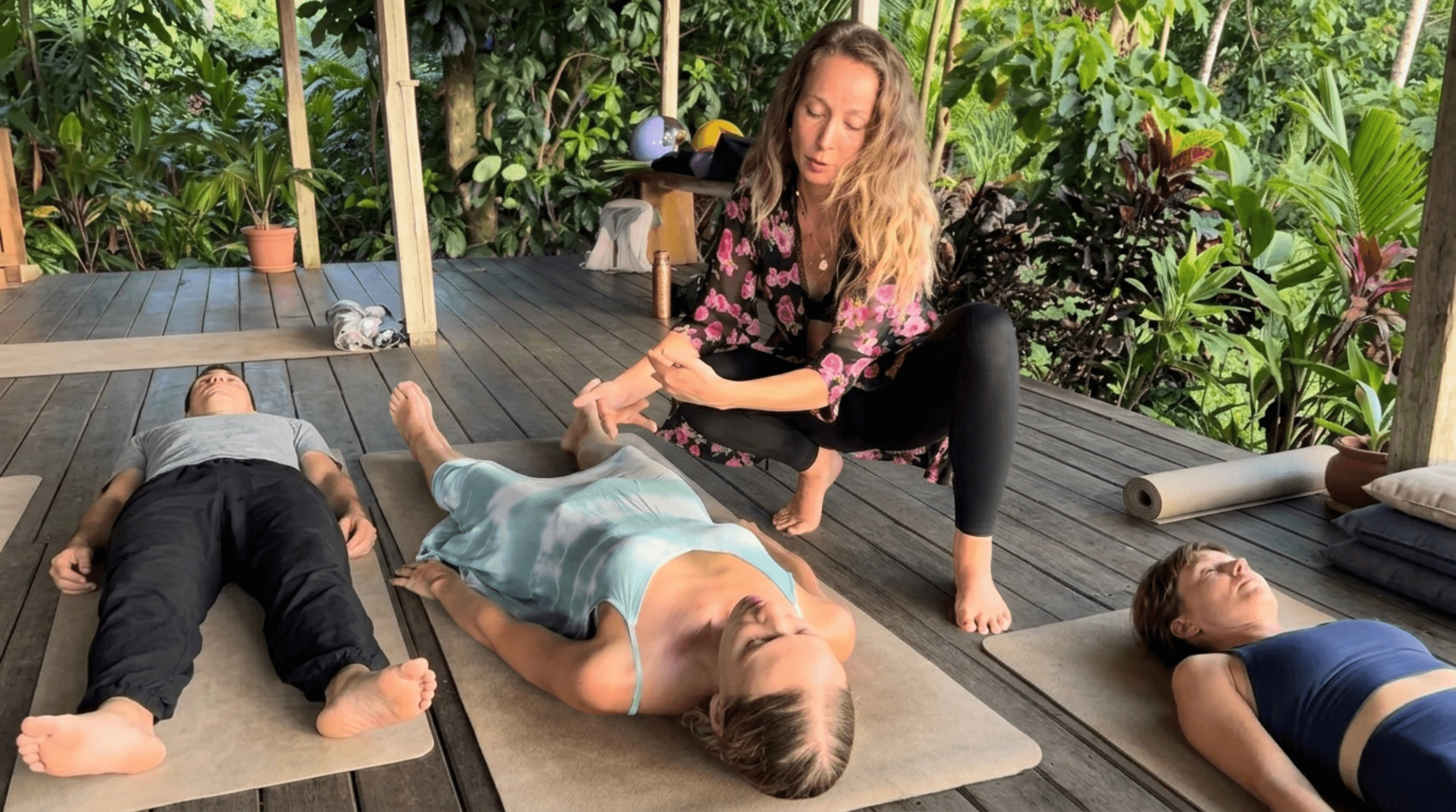 Facilitatorin begleitet eine Klientin bei einer energetischen Heilsession auf einer Matte.